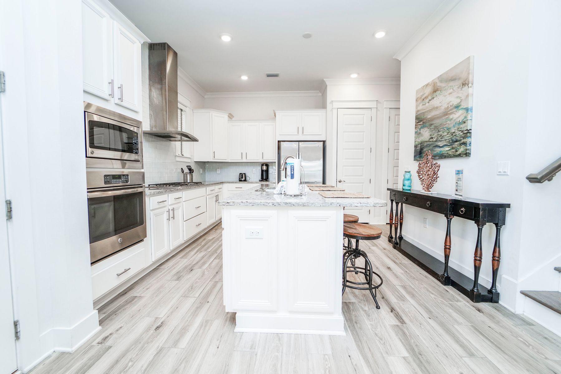 58 York Ln Inlet Beach, Unit B Inlet Beach, FL 32461 - Photo 5 of 24 a kitchen with stainless steel appliances kitchen island granite countertop a stove a sink and white cabinets with wooden floor
