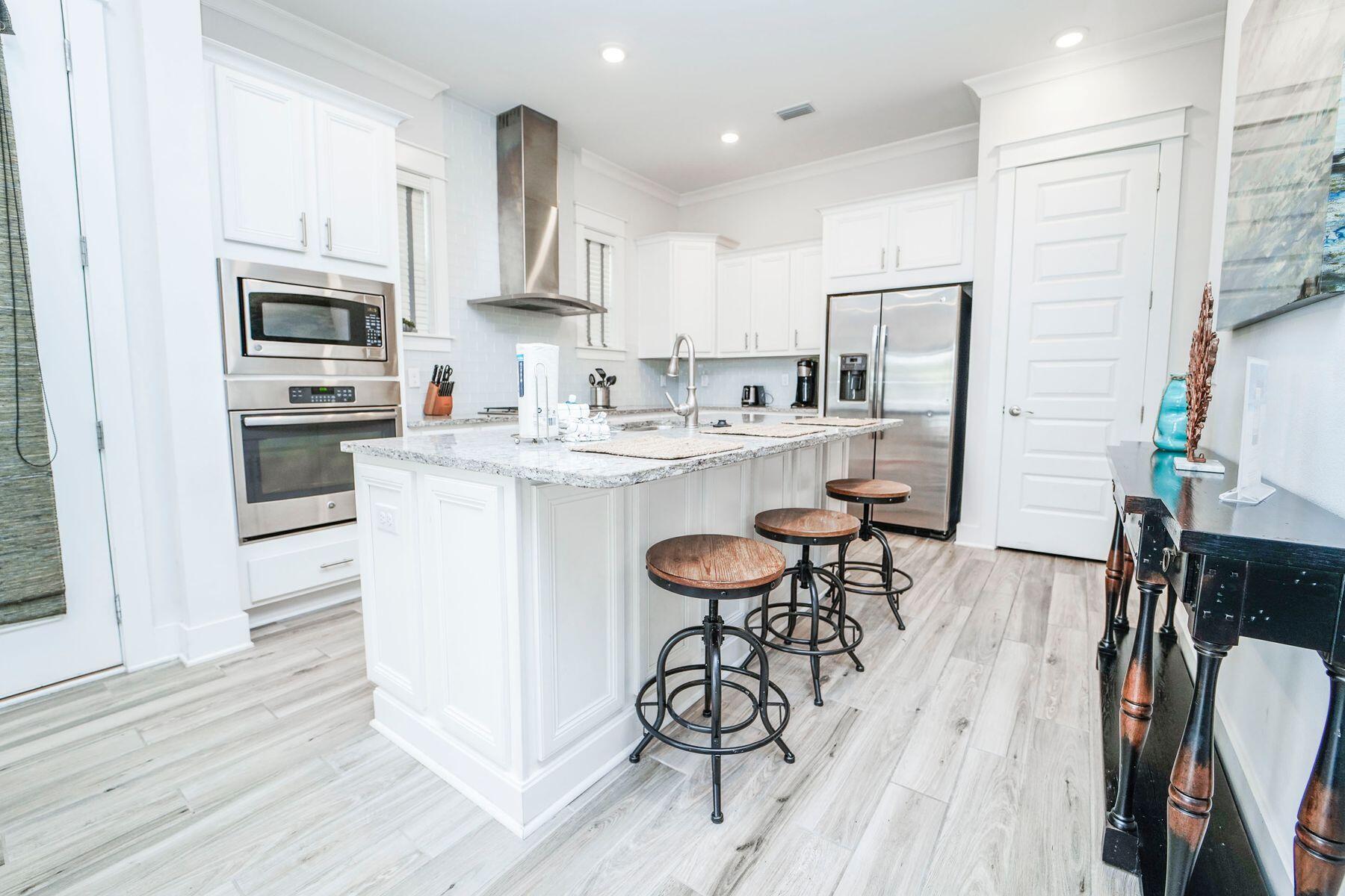 58 York Ln Inlet Beach, Unit B Inlet Beach, FL 32461 - Photo 7 of 24 a kitchen with stainless steel appliances a table chairs refrigerator and microwave