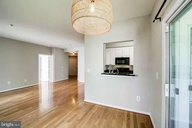 a view of a hallway with wooden floor and a bathroom