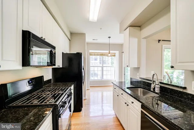 a kitchen with granite countertop lots of counter top space a sink a window and stainless steel appliances