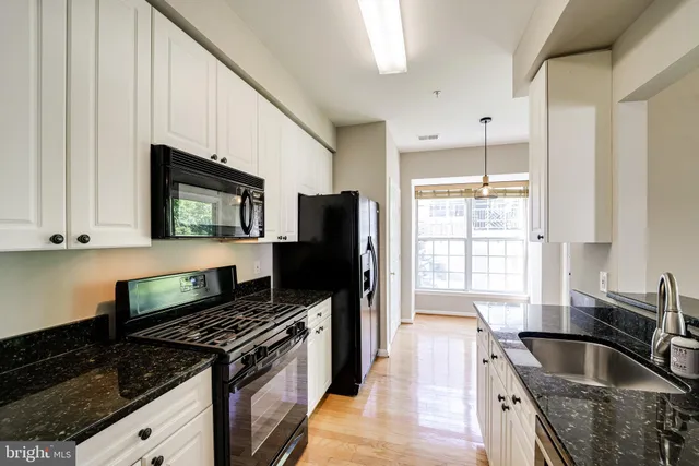 a kitchen with granite countertop a stove a sink and a microwave