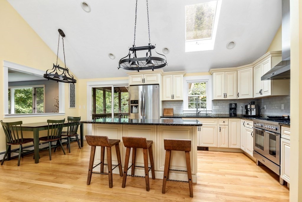 155 Whiting Street Hingham, MA 02043 - Photo 5 of 30 a kitchen with stainless steel appliances granite countertop a stove top oven a sink a dining table and chairs with wooden floor