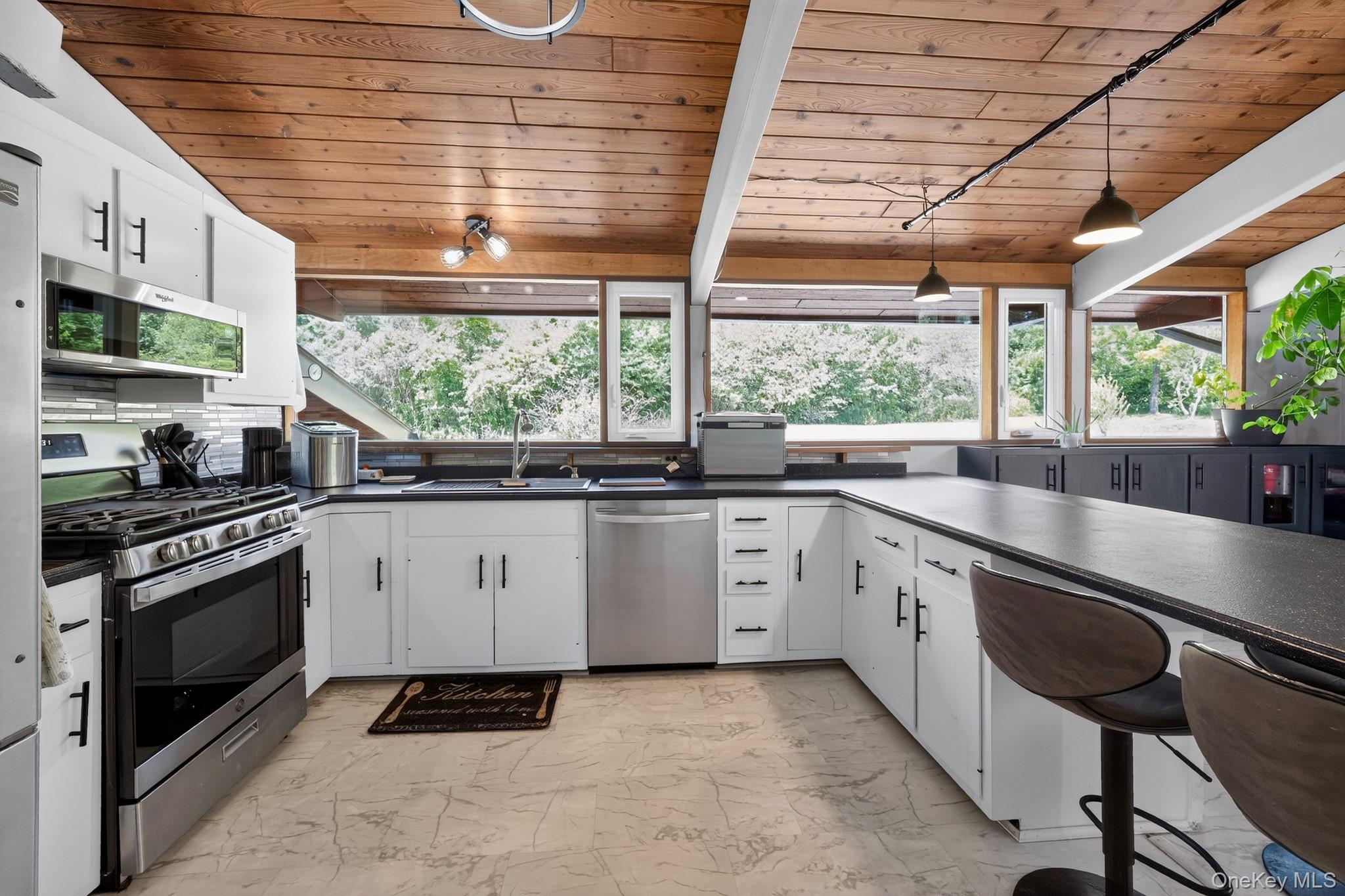 424 Laroe Road Chester, NY 10918 - Photo 2 of 43 Kitchen featuring a wood plank ceiling with exposed beams, white cabinetry, dark countertops, stainless steel appliances, and a tile backsplash