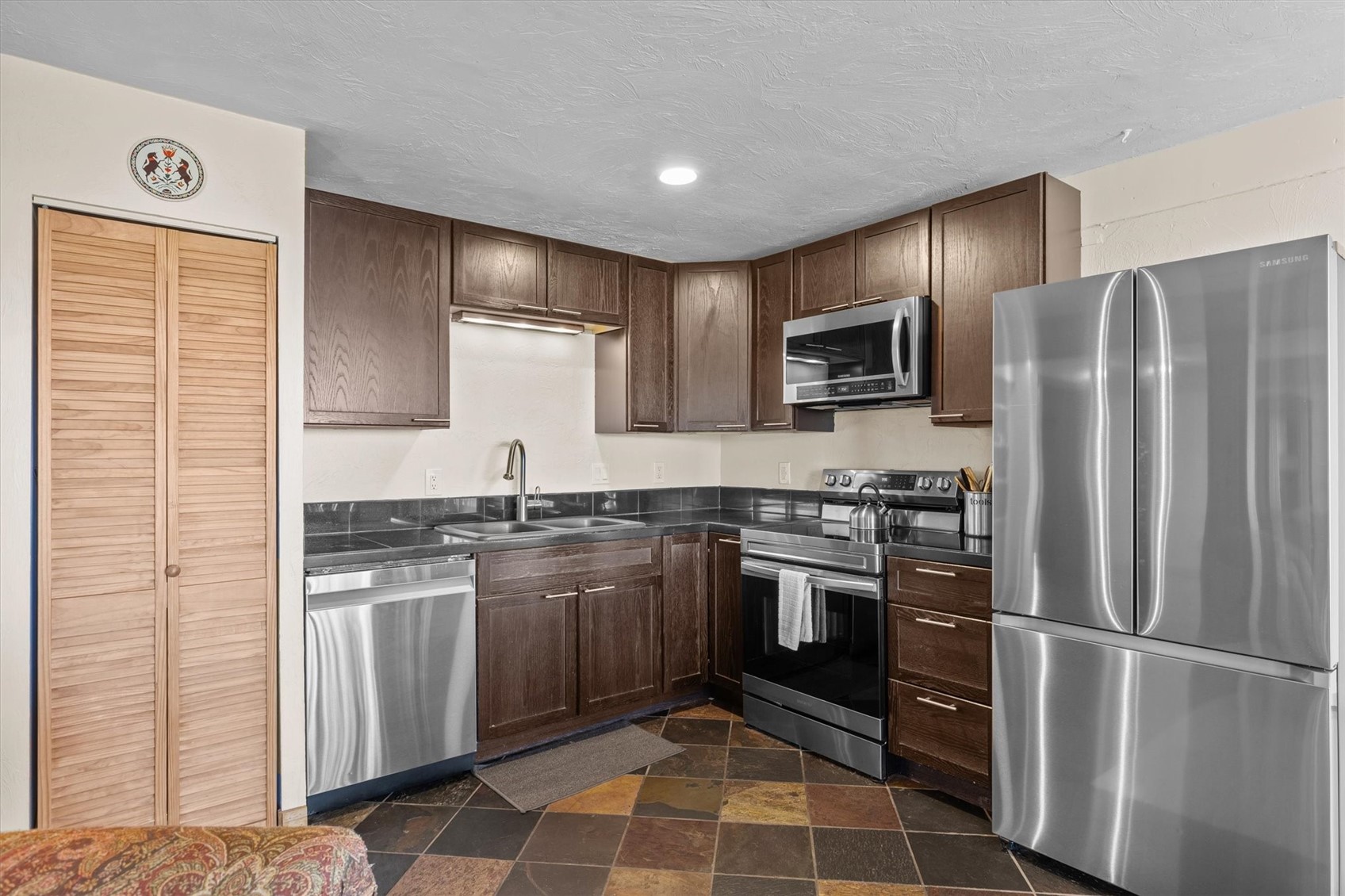 2602 Longthong Road, Unit 107 Steamboat Springs, CO 80487 - Photo 10 of 32 a kitchen with stainless steel appliances granite countertop a refrigerator sink and stove
