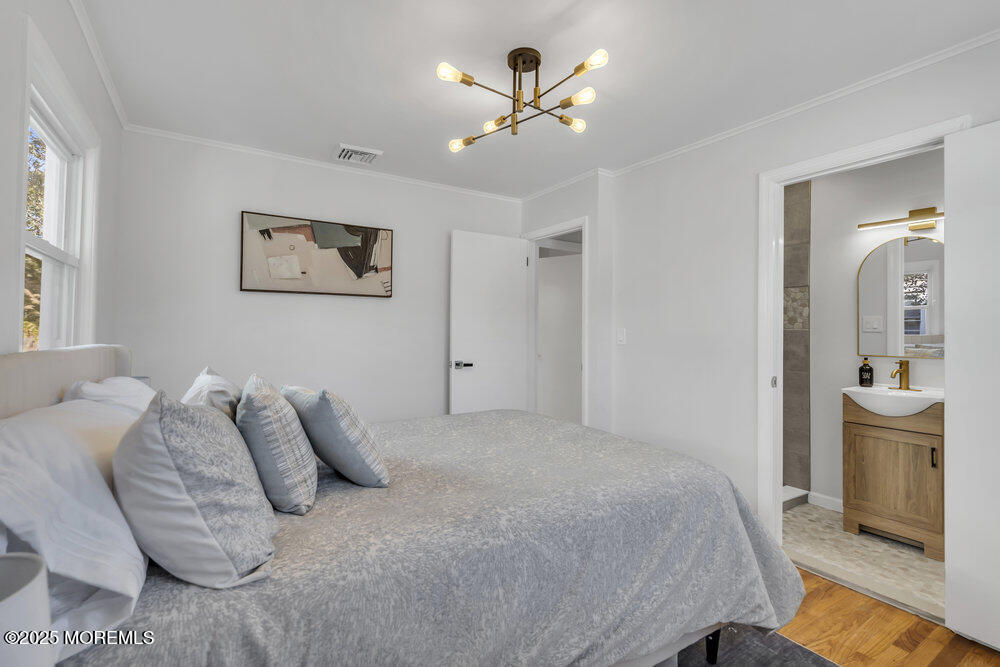 1202 Sunset Avenue Point Pleasant, NJ 08742 - Photo 12 of 23 a bedroom with a large bed and a chandelier