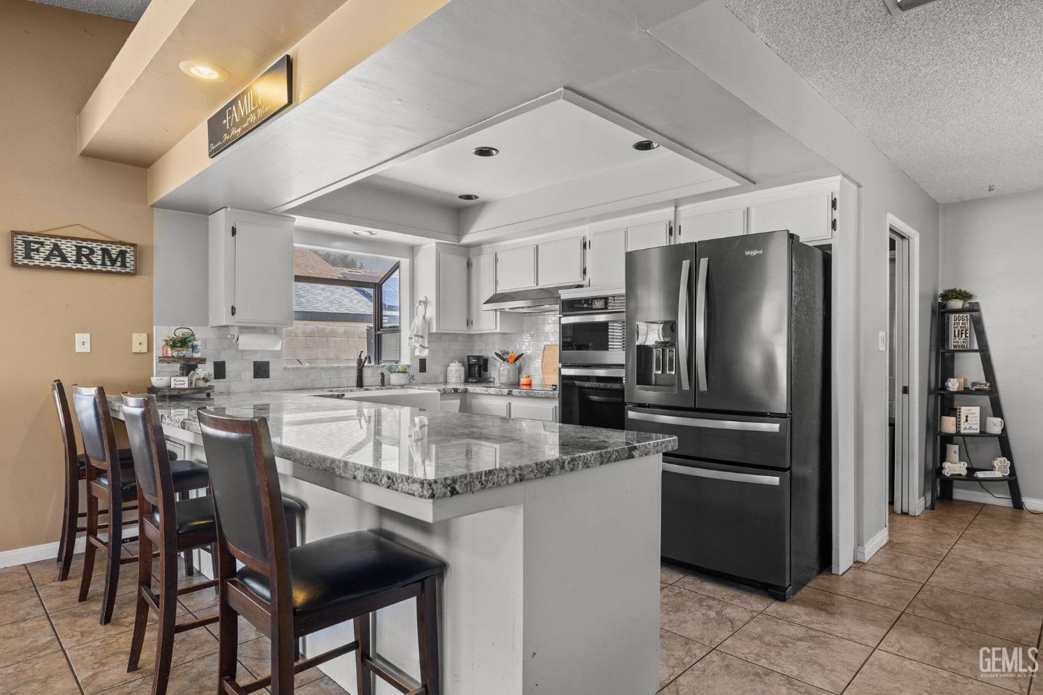 Undisclosed Address Bakersfield, CA 93311 - Photo 16 of 40 a kitchen with stainless steel appliances granite countertop a dining table chairs refrigerator and cabinets