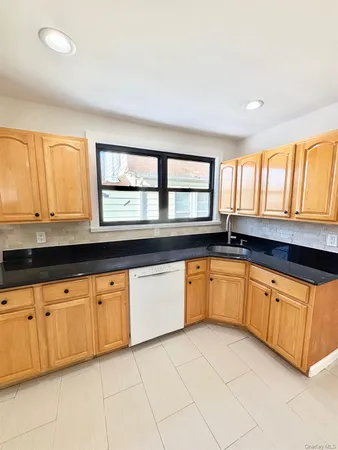 a large kitchen with granite countertop a sink and white cabinets
