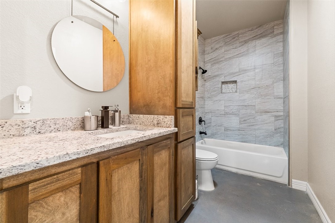 207 South Charles Street George West, TX 78022 - Photo 15 of 24 a bathroom with a granite countertop sink a toilet and a mirror