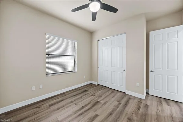 an empty room with wooden floor ceiling fan and windows