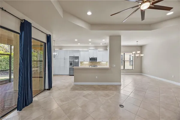 an empty room with chandelier fan and windows