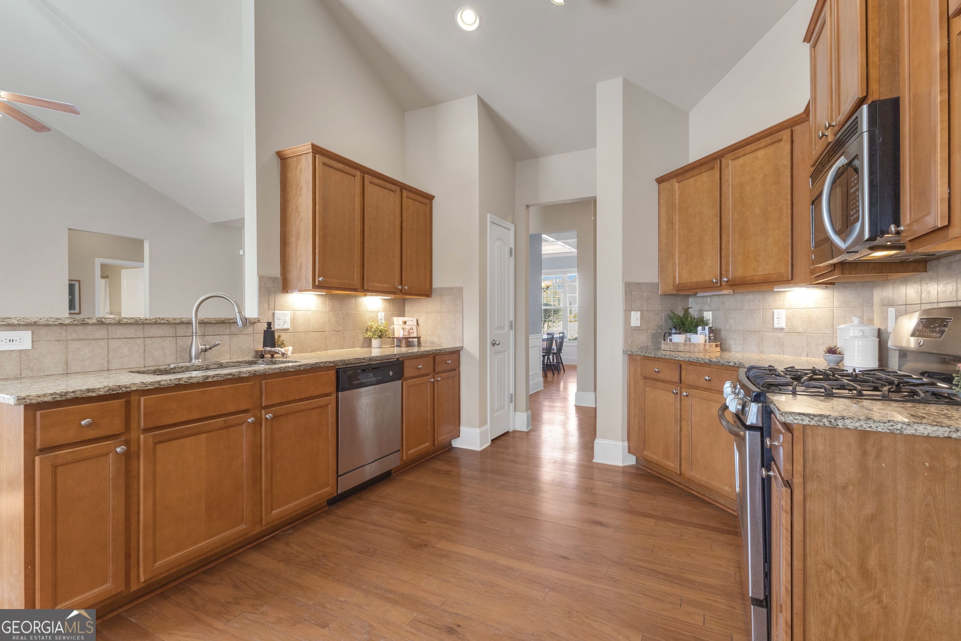 170 Savannah Drive Senoia, GA 30276 - Photo 26 of 60 a kitchen with stainless steel appliances granite countertop wooden cabinets a stove a sink and a wooden floor