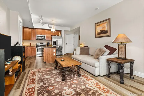 a living room with furniture and a dining table with kitchen appliances