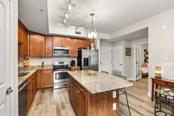 a kitchen with a stove a refrigerator a sink dishwasher a dining table and chairs with wooden floor