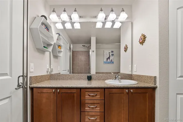 a bathroom with a granite countertop sink a large mirror and a shower