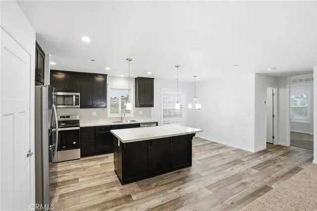 a kitchen with stainless steel appliances kitchen island granite countertop a sink refrigerator and cabinets