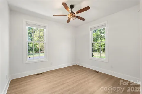an empty room with wooden floor and fan