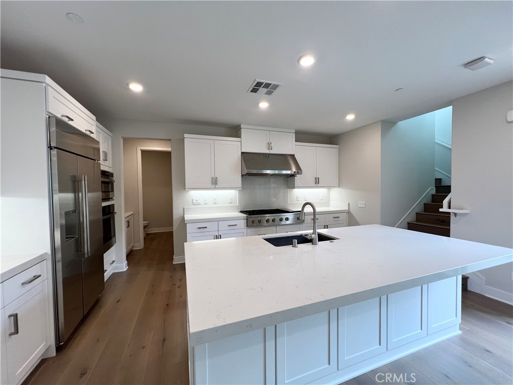 108 Chorus Irvine, CA 92618 - Photo 9 of 39 a kitchen with a refrigerator a stove and a sink with wooden floor