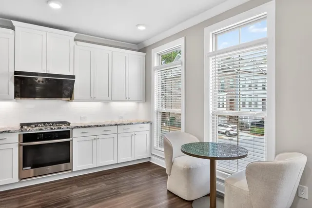 a kitchen with stainless steel appliances granite countertop a stove a microwave a dining table and chairs