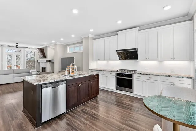 a kitchen with stainless steel appliances granite countertop a stove top oven a sink and white cabinets