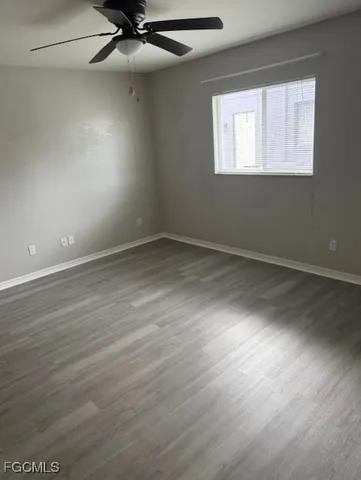 an empty room with wooden floor fan and windows