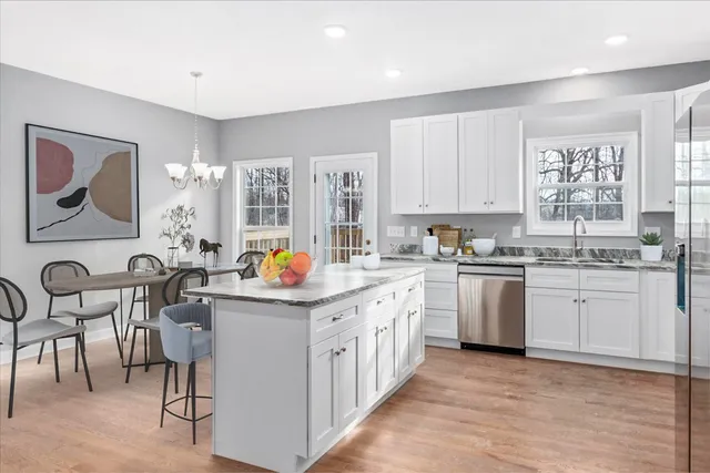 a kitchen that has a lot of white cabinets and wooden floor
