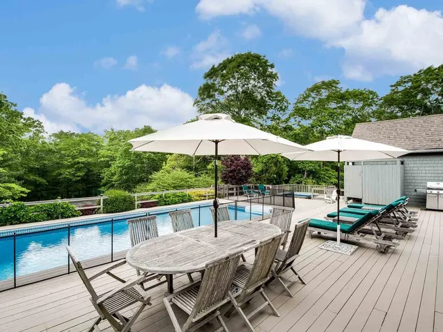 a view of a roof deck with table and chairs under an umbrella with wooden floor