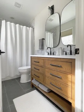 a bathroom with a double vanity sink toilet and a mirror