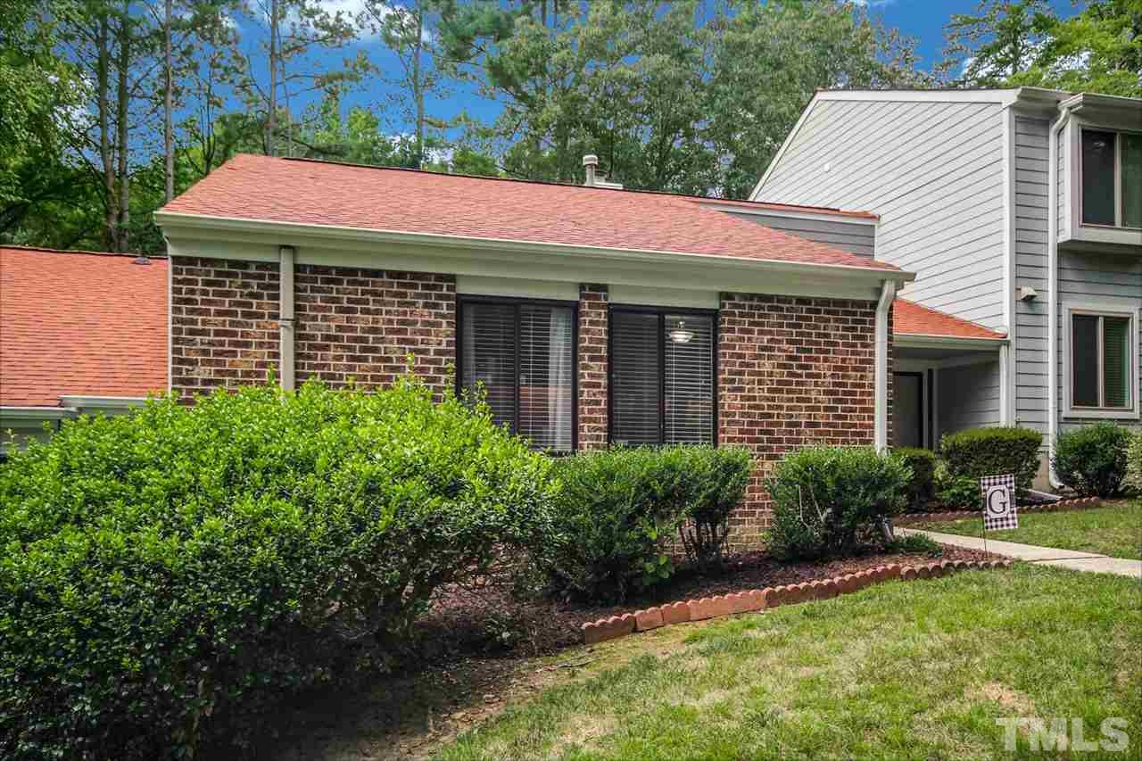 5863 Branchwood Road Raleigh, NC 27609 - Photo 2 of 30 a view of a house with brick walls and a yard with plants and a large tree