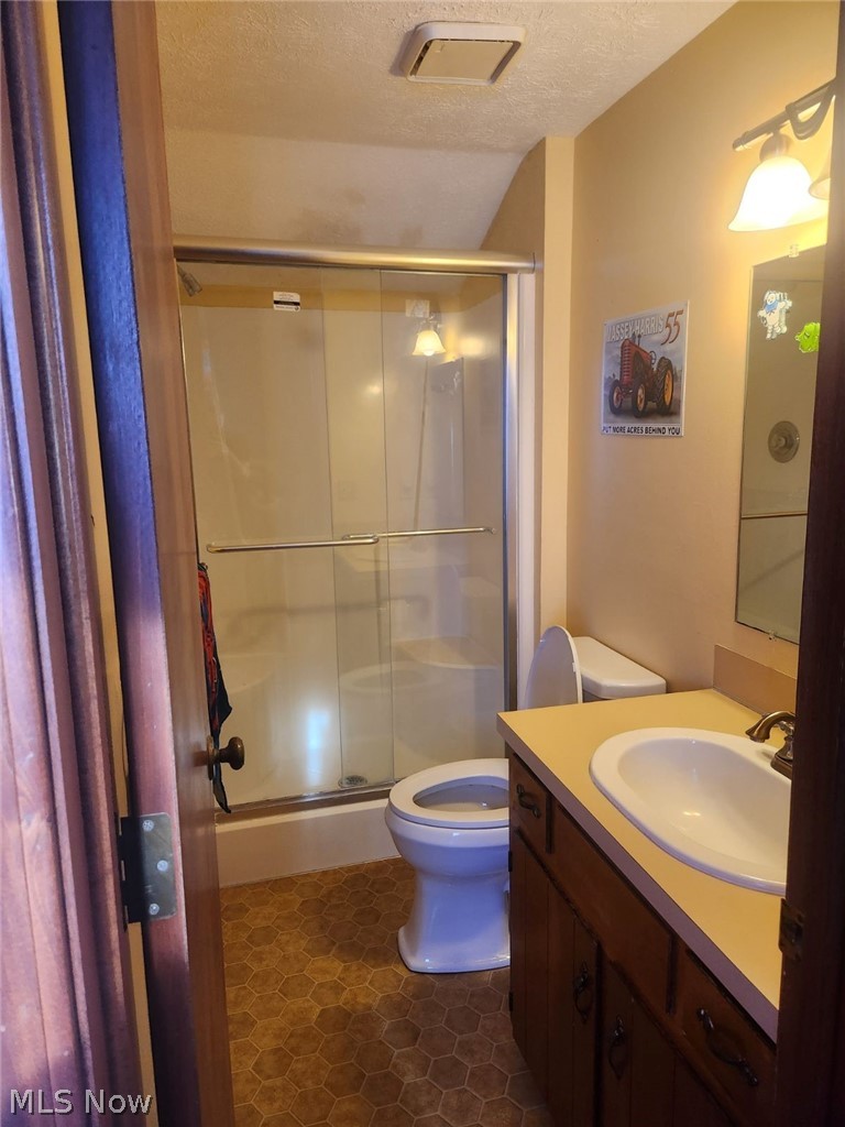 1166 Bass Circle Northwest Canton, OH 44708 - Photo 21 of 25 Bathroom featuring walk in shower, a textured ceiling, tile patterned floors, toilet, and vanity