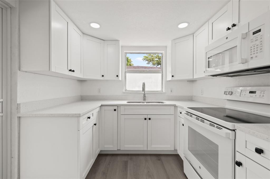 8046 Norwich Drive Port Richey, FL 34668 - Photo 12 of 31 a kitchen with white cabinets appliances and a window