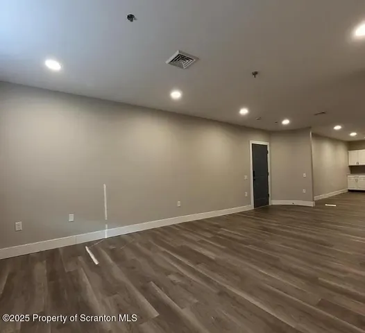 an empty room with wooden floor and natural light