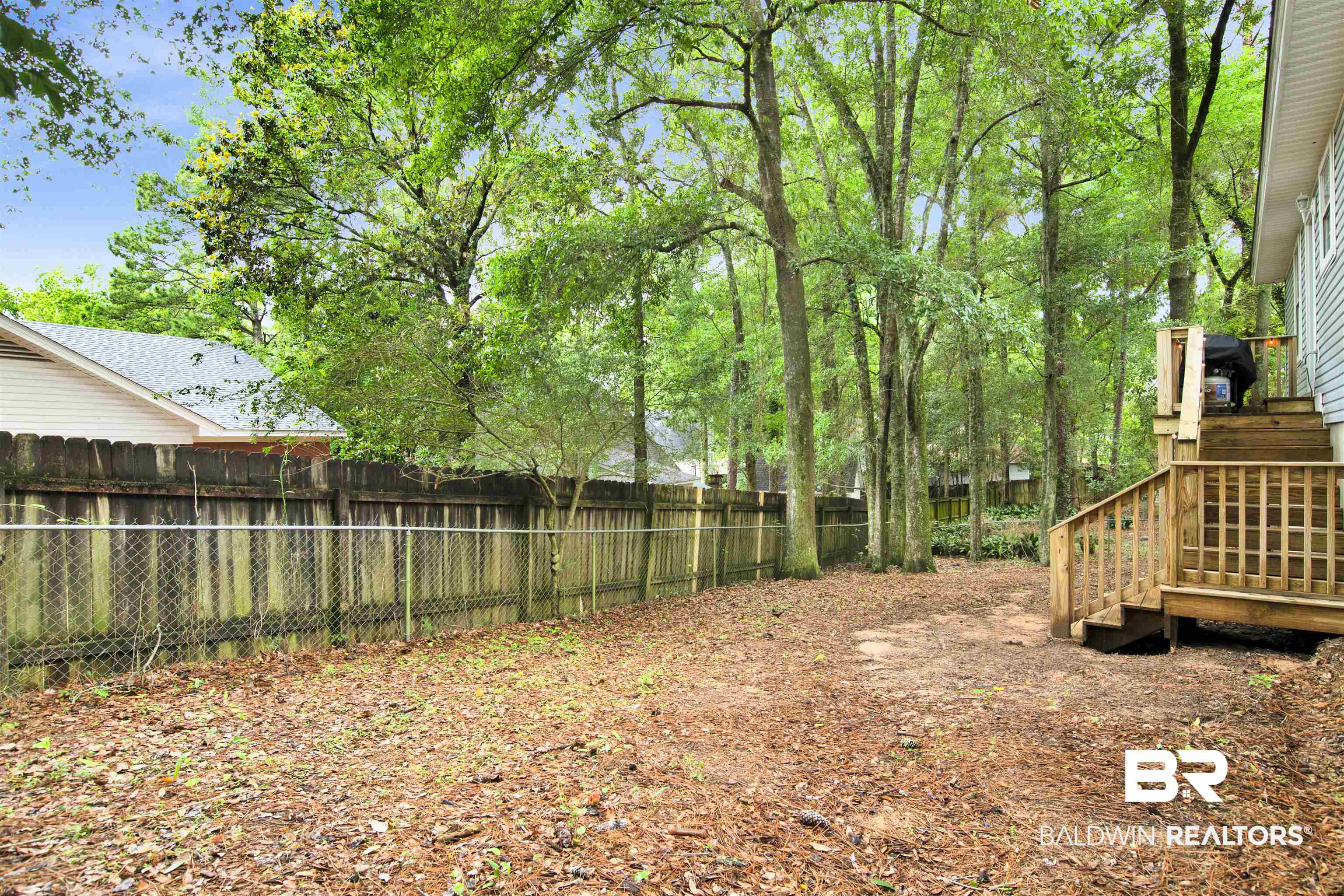 253 Maplewood Loop Daphne, AL 36526 - Photo 28 of 30 Expansive backyard featuring a wood privacy fence, mature trees, a multi-level wood deck, and an additional chain-link fence