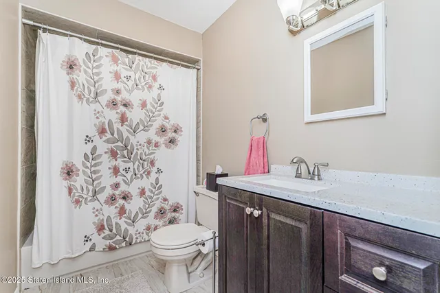 a bathroom with a granite countertop sink a toilet and a mirror