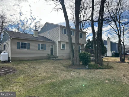 a view of a house with a yard deck and a large tree