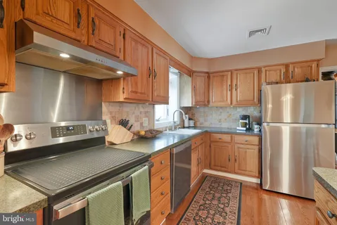 a kitchen with stainless steel appliances a stove a sink a refrigerator and cabinets