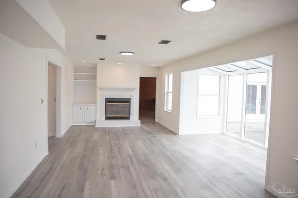 a view of an empty room with a window and wooden floor