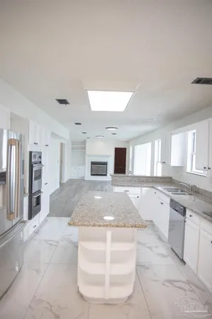 a large kitchen with kitchen island a sink a stove a refrigerator and white cabinets