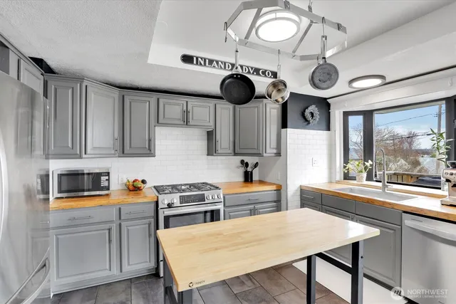 a kitchen with stainless steel appliances a stove a sink cabinets and a dining table