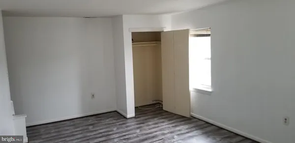 a view of an empty room with wooden floor and closet