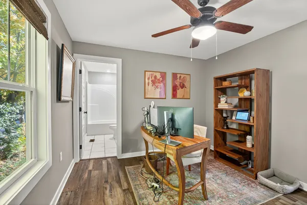 a work room with furniture a bookshelf and a window