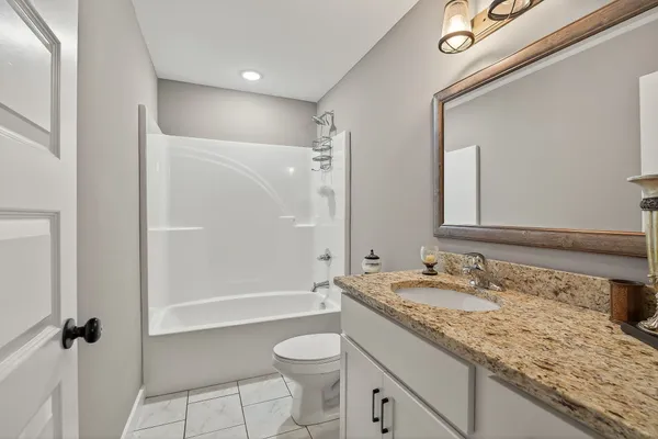 a bathroom with a granite countertop sink toilet and shower