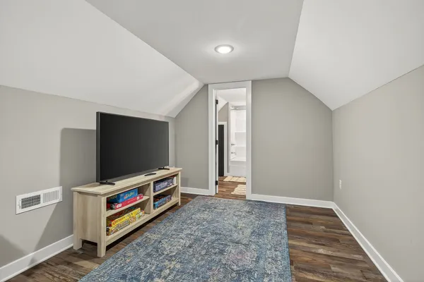 a view of an empty room with wooden floor and a flat screen tv