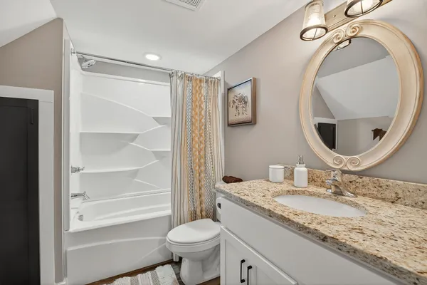 a bathroom with a granite countertop sink mirror vanity and a toilet