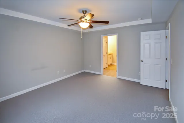 an empty room with a window and a chandelier fan
