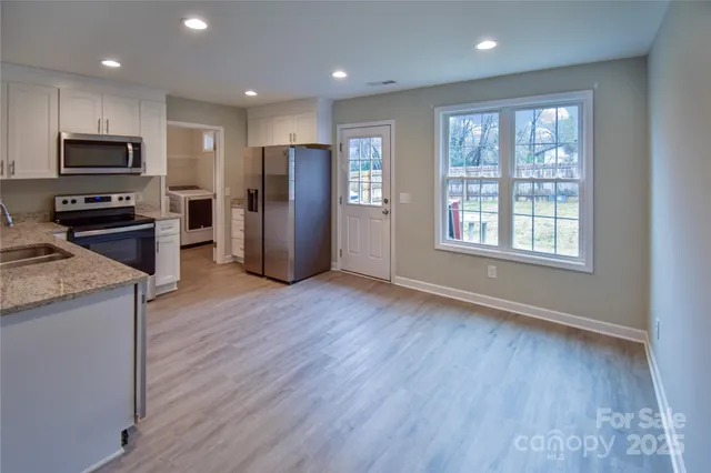 an open kitchen with a refrigerator and wooden floor