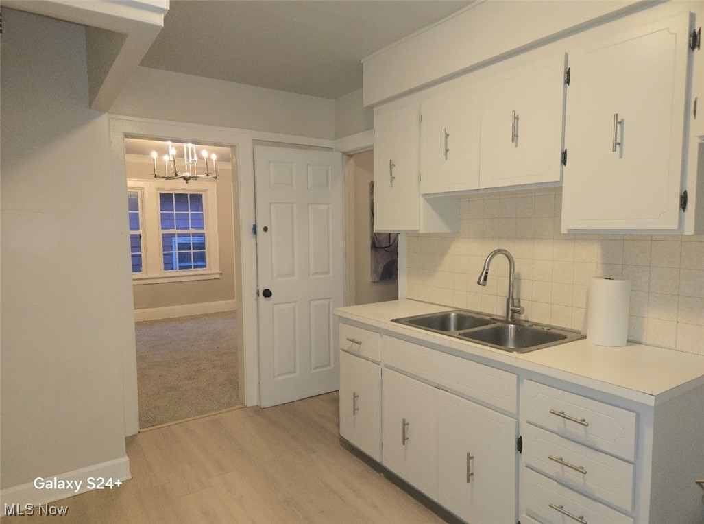 3571 Riedham Road Cleveland, OH 44120 - Photo 11 of 24 Kitchen with backsplash, white cabinetry, sink, and light hardwood / wood-style flooring