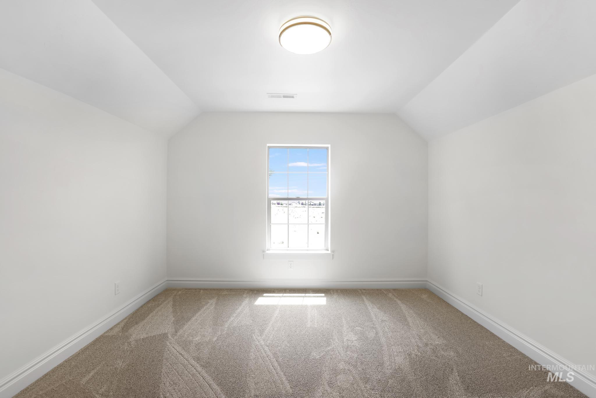 866 Quartz Road Kimberly, ID 83341 - Photo 31 of 48 Spacious room featuring vaulted ceilings, a central flush-mount light fixture, a window with exterior scenery, plush carpet flooring, and white baseboards