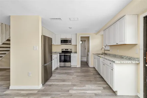 a kitchen with granite countertop white cabinets and stainless steel appliances