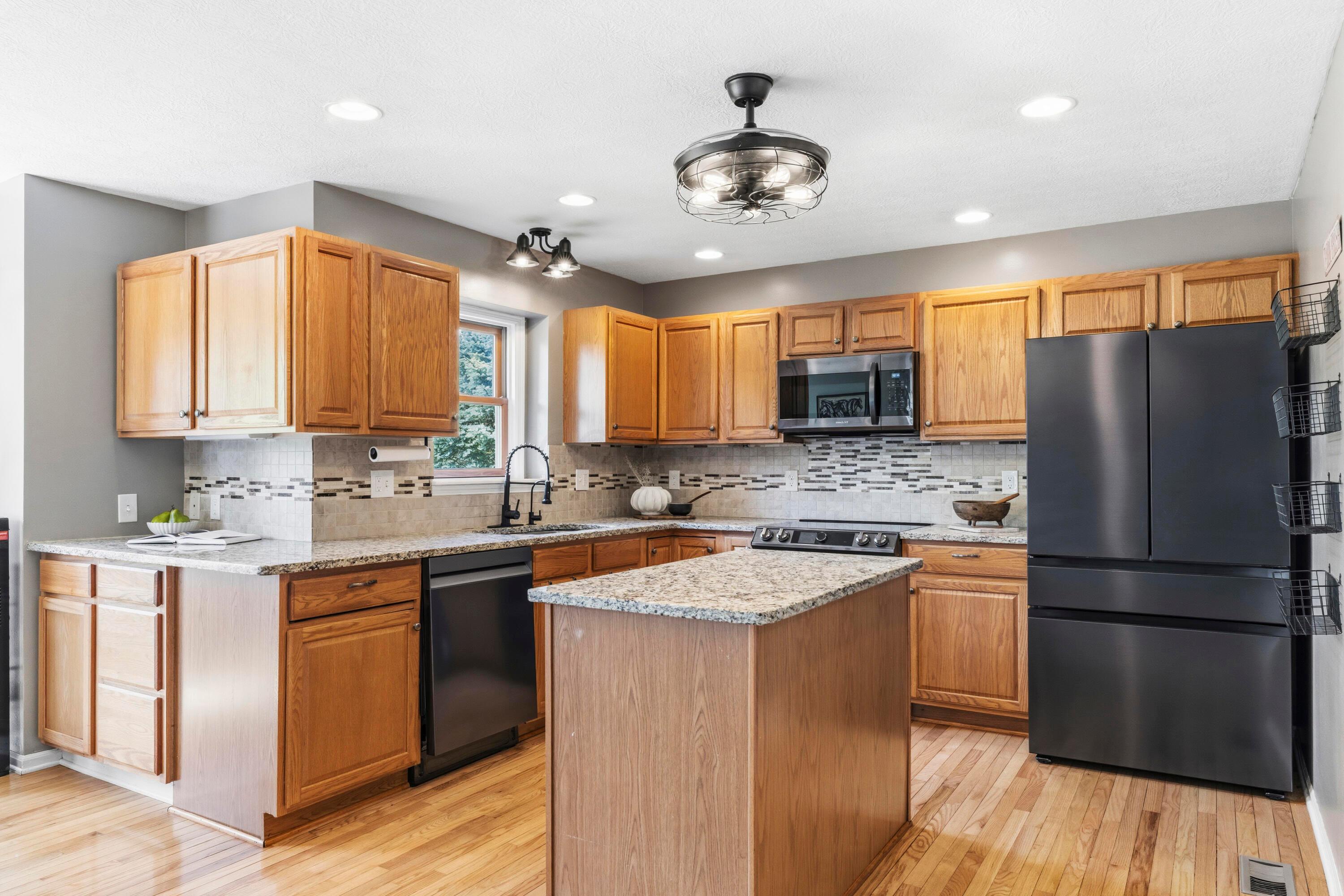 8507 Benner Road Johnstown, OH 43031 - Photo 18 of 69 Large Kitchen with hardwood floors and Dining Area with bay window & double fireplace! Granite countertops, island, NEW Black Stainless Steel Appliances, including an induction oven! NEW Reverse Osmosis to sink/Fridge/Brio+