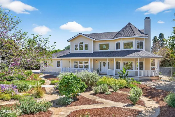 a front view of a house with a yard and potted plants